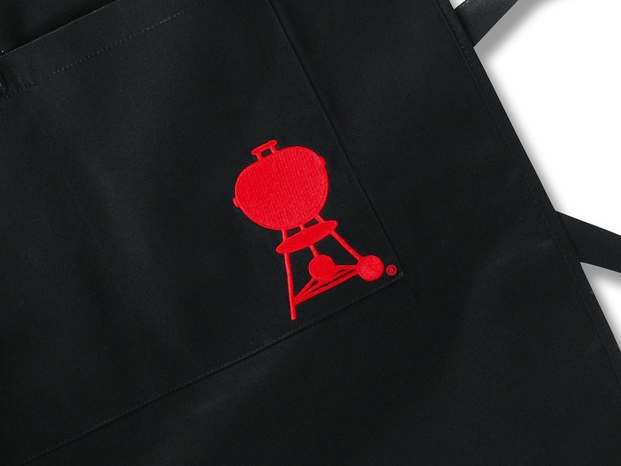 Schwarze Schürze mit rot gestickter Weber-Kugelgrill-Marke